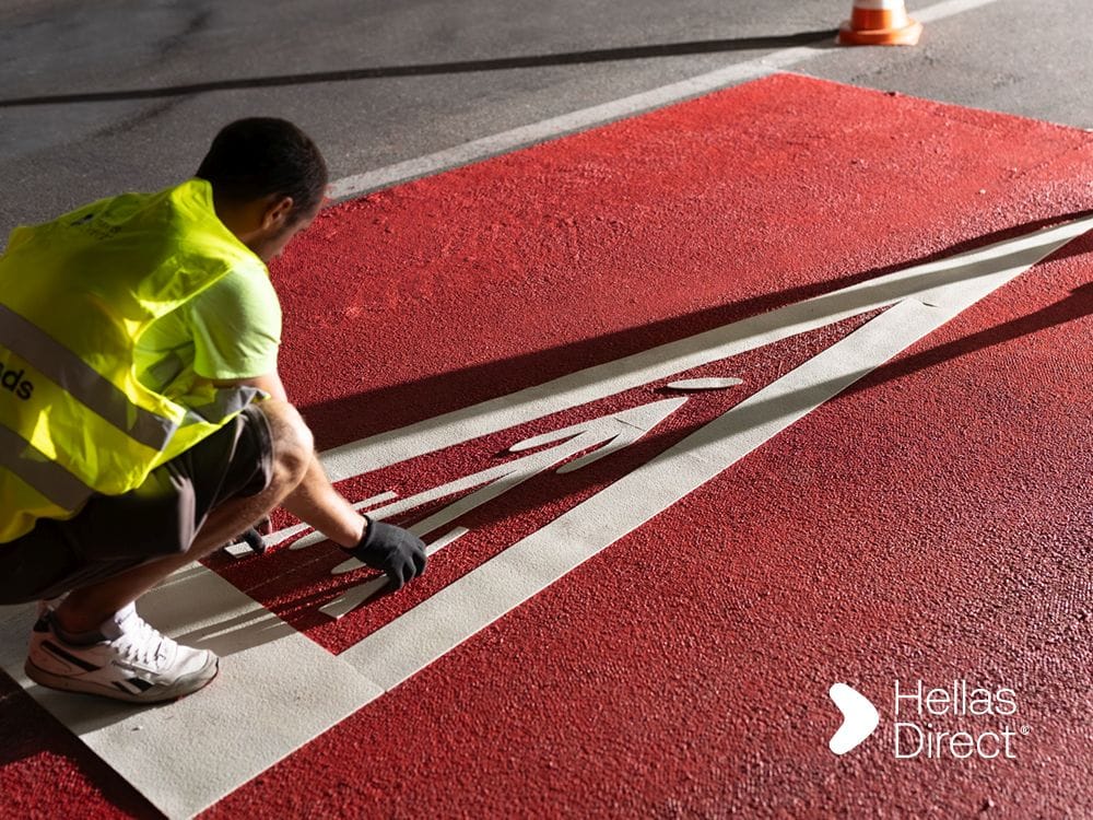 A man of the Safe Roads Project crew fixes a sign on a crosswalk outside a school