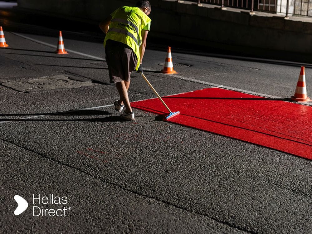 A man of the Safe Roads Project crew paints a crosswalk outside a school